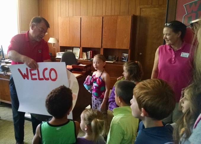 President Fuller holds up one of the signs as a young girl talks to him
