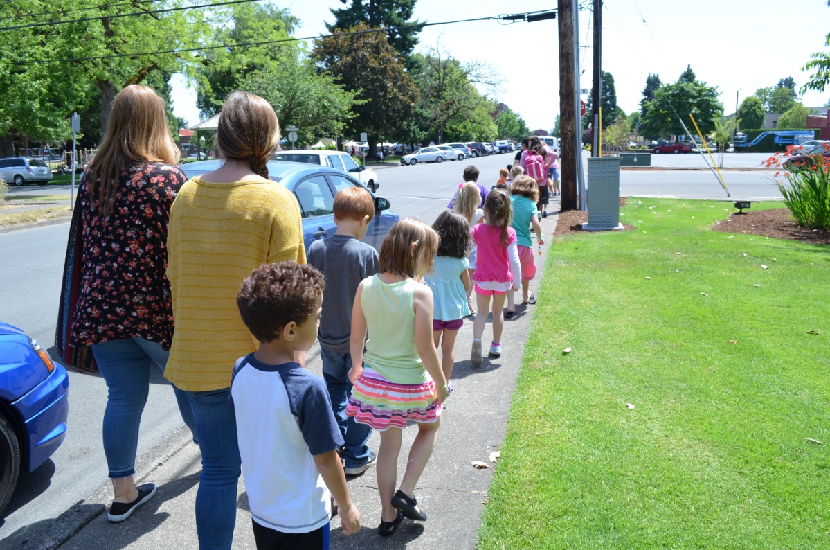children and adults walking up a street
