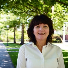 Dr. Patricia Blasco smiles in front of a background of trees