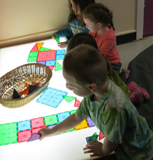 learning through play - children with shapes on a light table